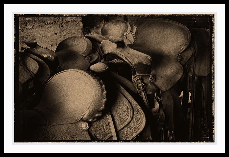 4 Saddles waiting to be used. Sepia tone with rustic frame.